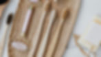There are a bunch of bamboo toothbrush on a wooden tray on a white marble table