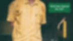 A man is standing with a yellow shirt on in a dark room and there is a person behind him