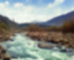 This is a picture of Manali, there is a river, a lot of trees and rocks
