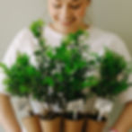 A happy woman holding plants with eco-friendly pots.