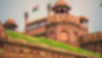 Red Fort - Historic red sandstone fort with an Indian flag waving atop, set against a clear sky. The structure features intricate domes and arches.