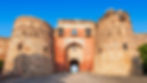 Ancient stone old fort / Purana Qila with two large circular towers and a central arched entrance. Clear blue sky above, creating a historic and majestic vibe.