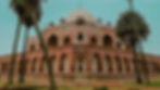 Humayun's Tomb - Historic red and white building with arches and large dome, surrounded by tall palm trees, under a clear blue sky. Peaceful setting.